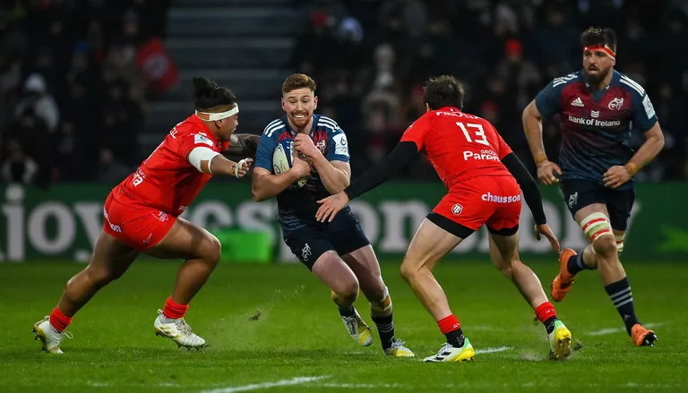 Munster's Ben Healy carrying the ball into David Ainu'u and Pierre-Louis Barassi of Toulouse