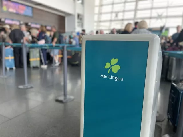 An Aer Lingus desk in the foreground, with passengers queuing behind