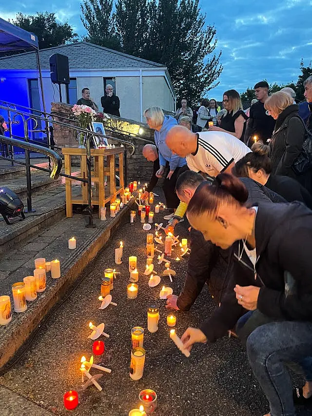 People lay candles at a vigil for the boys