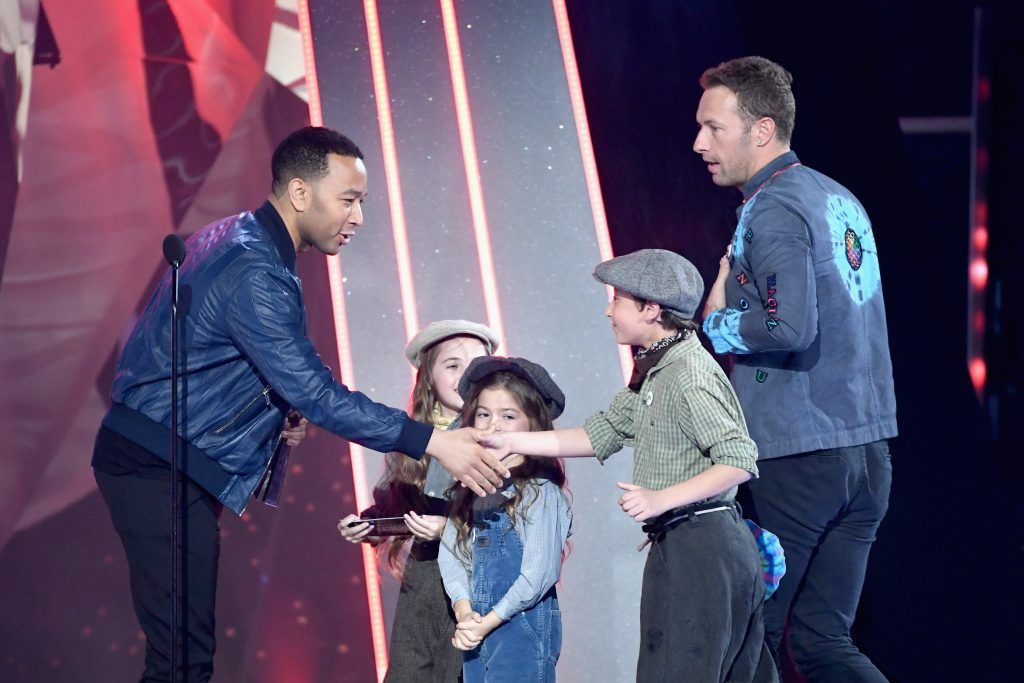 Singer Chris Martin of Coldplay (R) accepts Best Tour from musician John Legend (L) and youth dancers onstage at the 2017 iHeartRadio Music Awards which broadcast live on Turner's TBS, TNT, and truTV at The Forum on March 5, 2017 in Inglewood, California.  (Photo by Kevin Winter/Getty Images for iHeartMedia)
