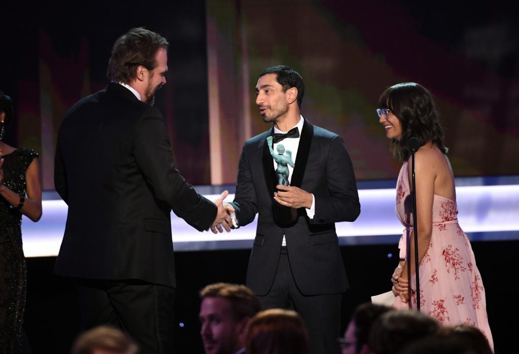 LOS ANGELES, CA - JANUARY 29:  (L-R) Actor David Harbour of 'Stranger Things' accepts Outstanding Performance by an Ensemble in a Drama Series from actors Riz Ahmed and Rashida Jones onstage during The 23rd Annual Screen Actors Guild Awards at The Shrine Auditorium on January 29, 2017 in Los Angeles, California. 26592_014  (Photo by Kevin Winter/Getty Images )