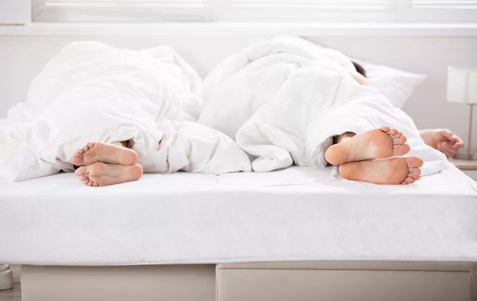 Couple sleeping in bed with separate duvets