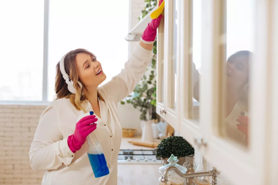 Woman listening to music while cleaning cupboards in kitchen