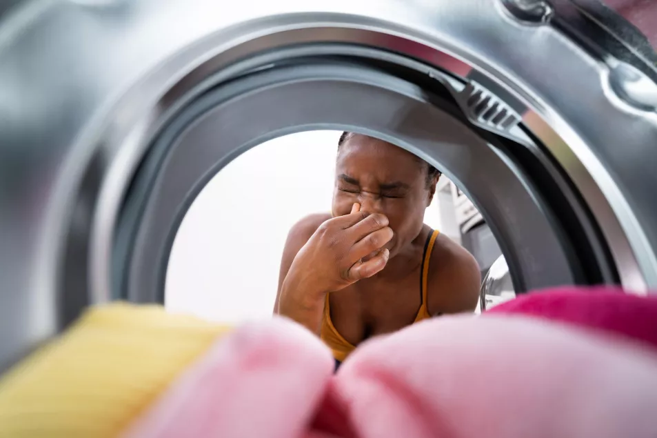 Woman looking inside smelly washing machine