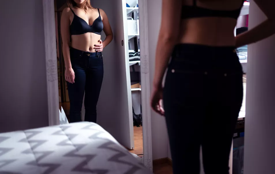 woman looking at stomach in mirror