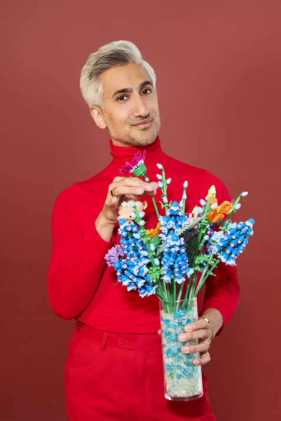 Tan France holding a vase of faux flowers