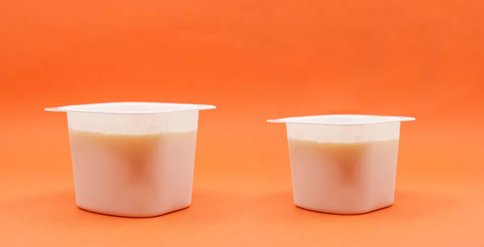 A smaller yoghurt beside a bigger one