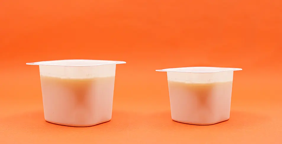 A smaller yoghurt beside a bigger one