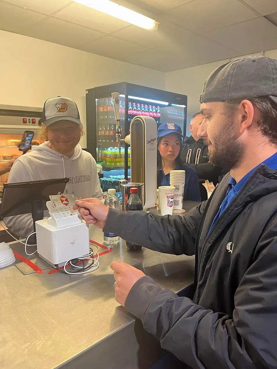 Ed Sheeran serving a pint to a punter at the Portman Road stadium in Ipswich 