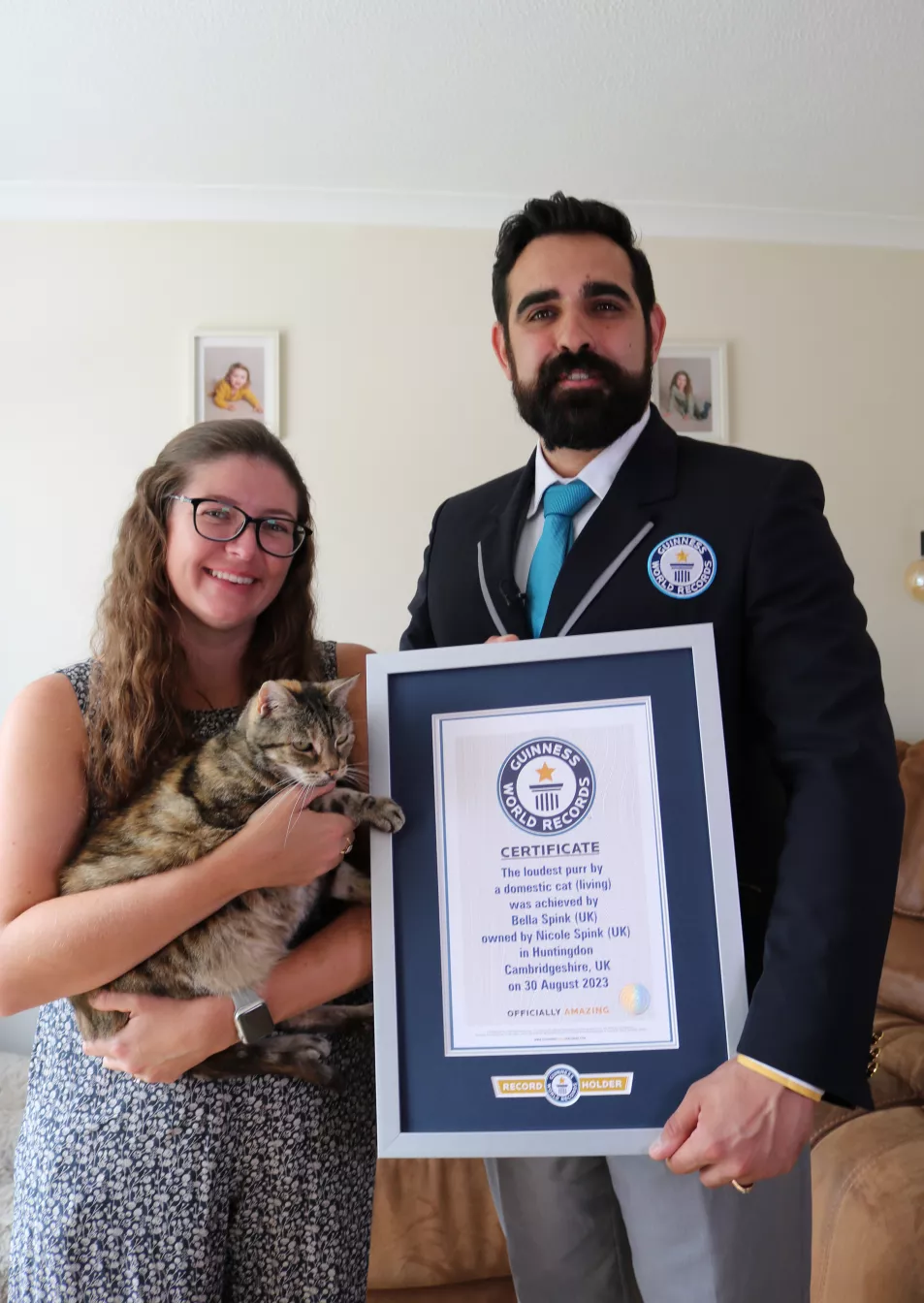 Cat owner holding pet stood next to Guinness World Record adjudicator holding certificate