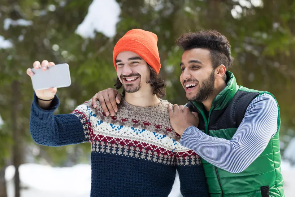 Gay male couple outside in the snow taking a selfie