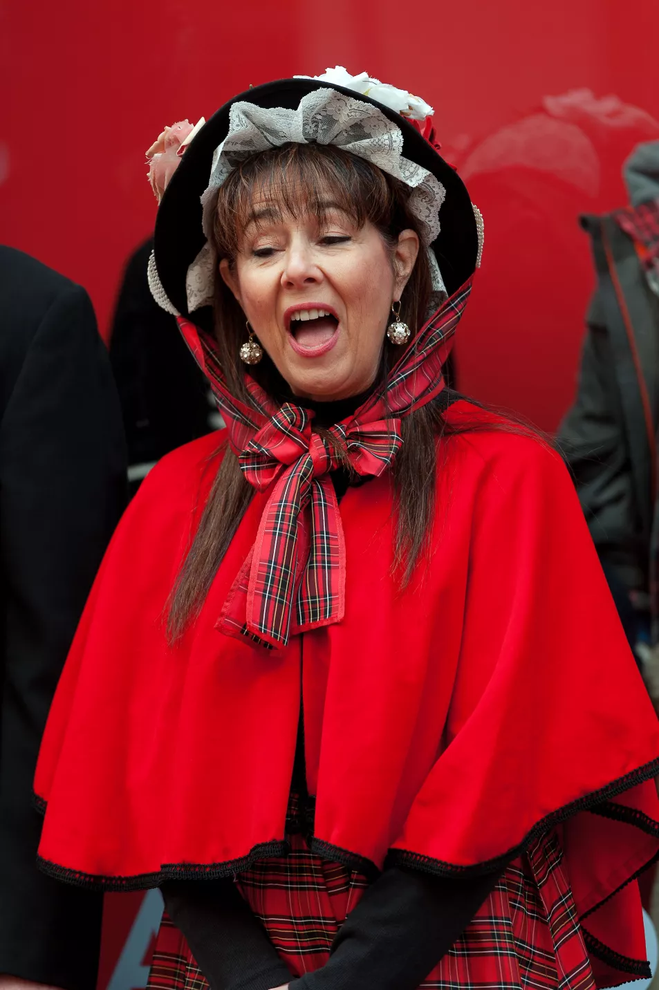 Woman wearing red Victorian caroler outfit singing