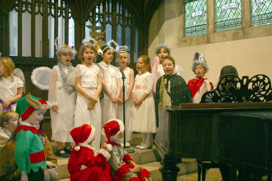Christmas primary school celebration with children dressed up and singing carols in church