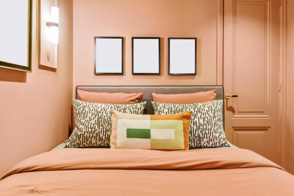 Peach bedroom with many paintings and a bed covered with a peach fluffy bedspread