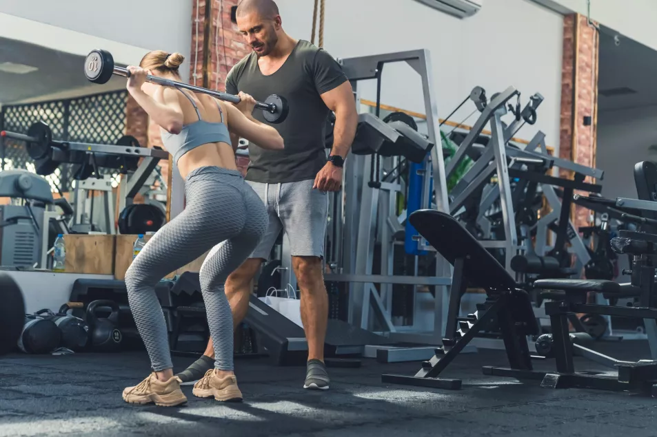 Woman working out in gym with personal trainer