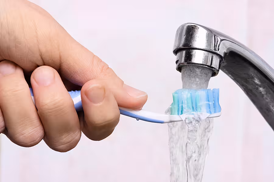 hand washing toothbrush under running water