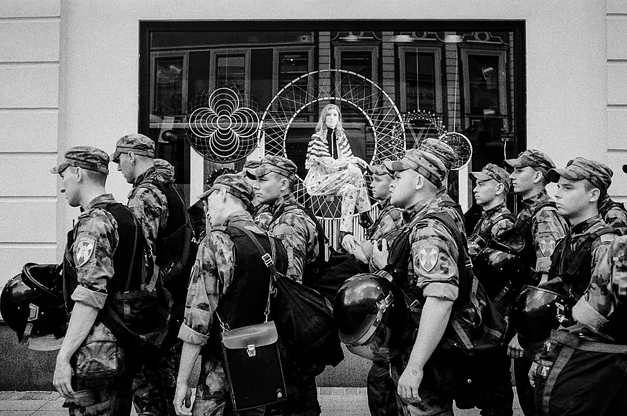 Camo clad troops pass by a shop window