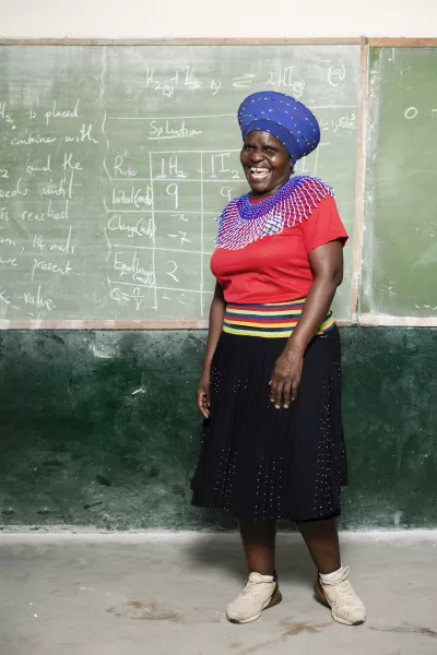 A laughing woman in front of a blackboard