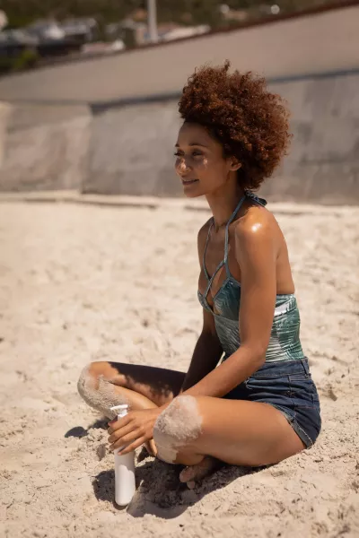 Woman with sunscreen lotion relaxing on the beach