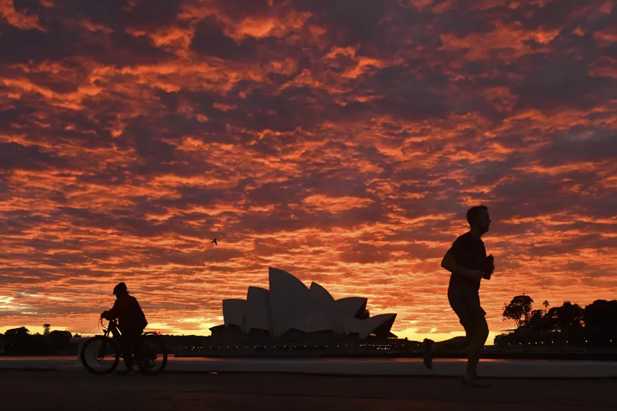 A jogger runs past the Sydney Opera House at dawn 