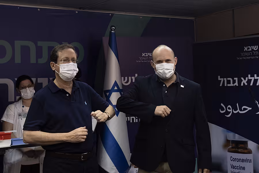 Israeli president Isaac Herzog, left, bumps elbows with prime minister Naftali Bennett after receiving his booster jab 