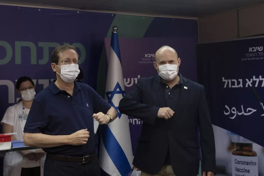 Israeli president Isaac Herzog, left, bumps elbows with prime minister Naftali Bennett after receiving his booster jab 