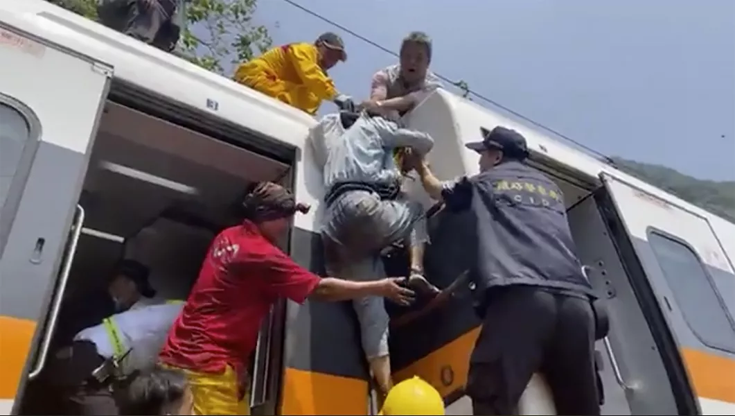 A passenger is helped to climb out of a derailed train in Hualien County