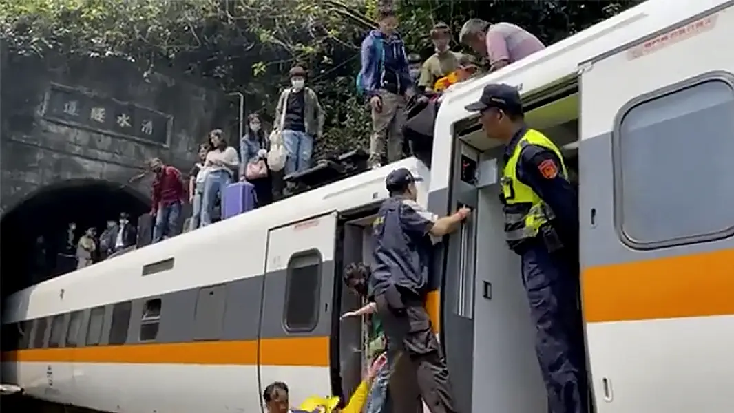 Passengers climb onto the roof of the derailed train