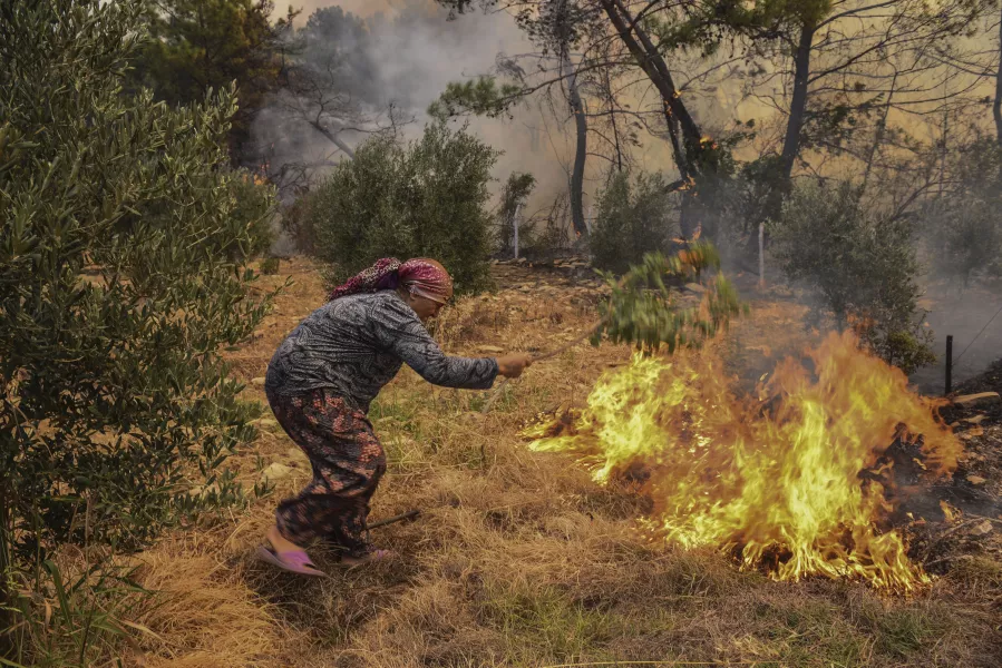 A woman tries to stop an advancing wildfire in Turkey