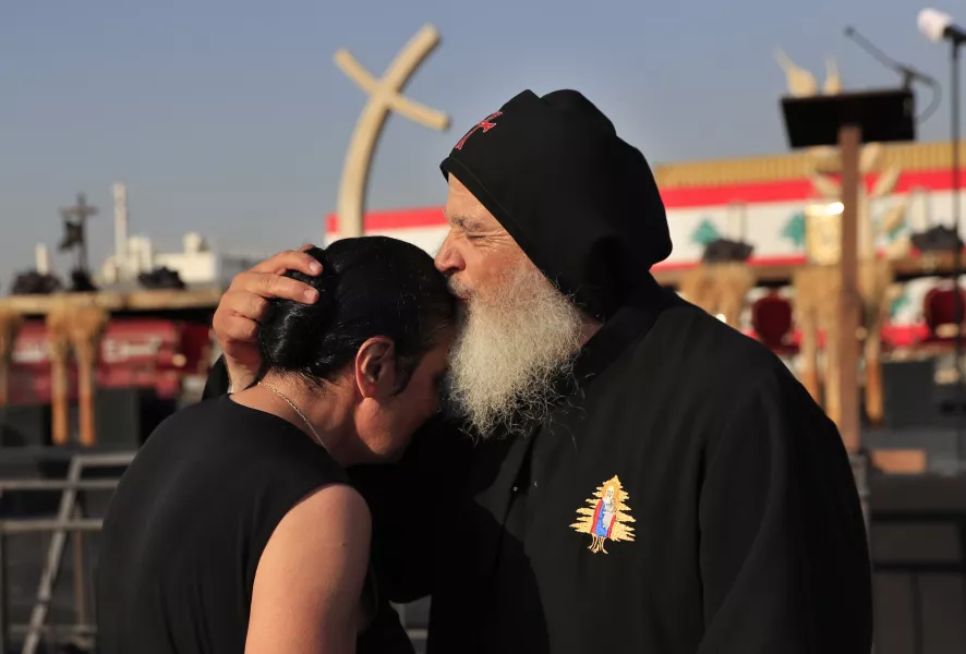A priest kisses and comforts a relative of a Beirut port blast victim