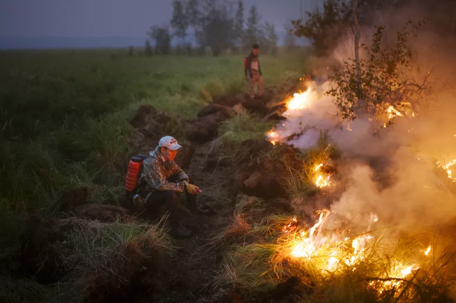 Volunteers work at the scene of a forest fire near Kyuyorelyakh village