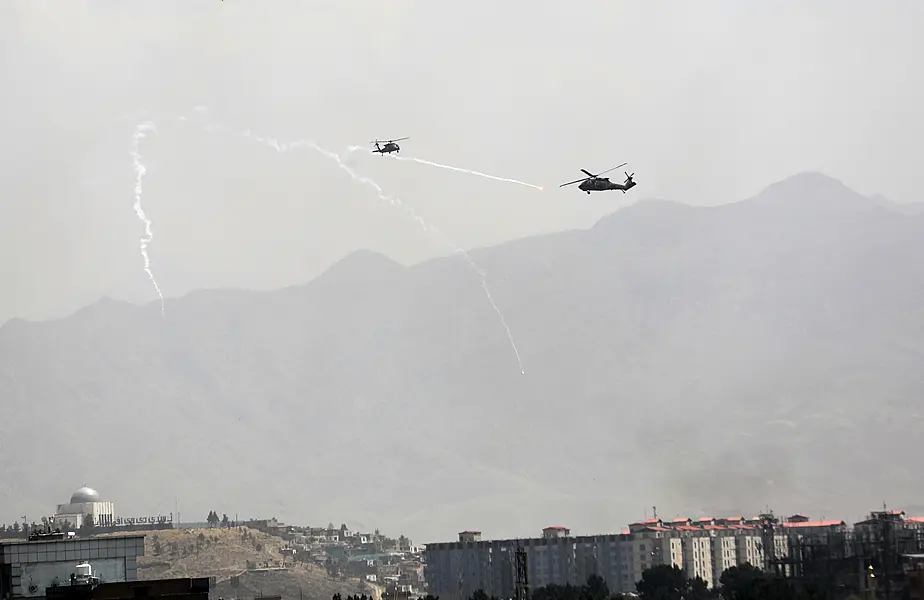 Anti-missile decoy flares are deployed as US Black Hawk military helicopters fly over the city of Kabul, Afghanistan