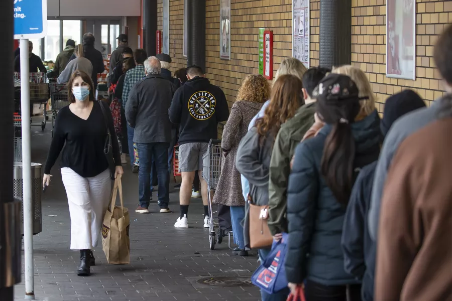 Shoppers queue to enter a supermarket in Auckland, New Zealand