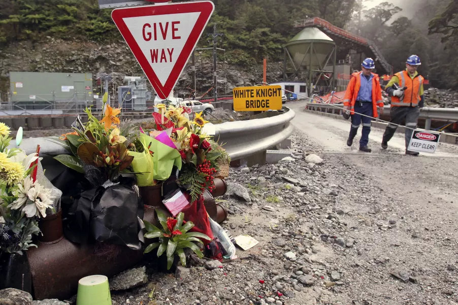 Workers walk past a bouquet of flowers for victims of mine explosion at the Pike River mine at Greymouth, New Zealand in 2011