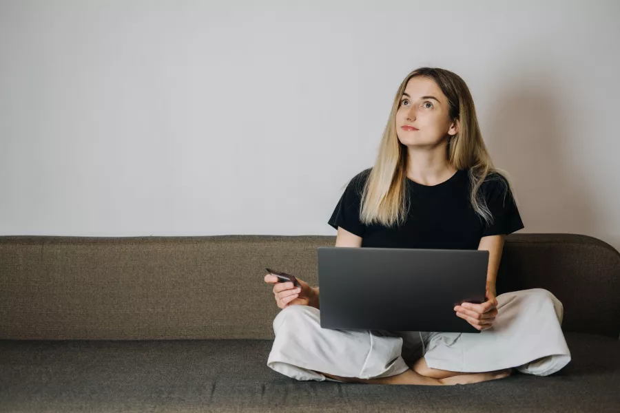 Woman sitting on sofa doing online shopping on laptop