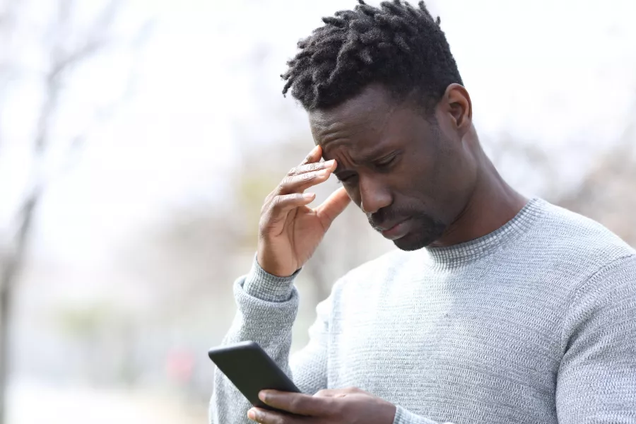 Worried black man reading bad news on smart phone