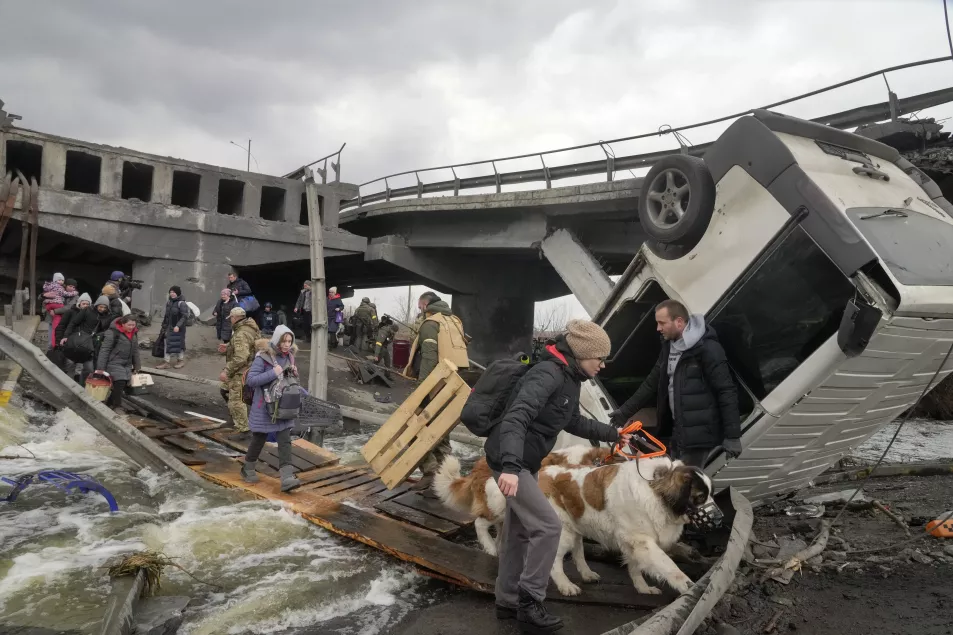 People cross an improvised path under a destroyed bridge while fleeing the town of Irpin close to Kyiv 