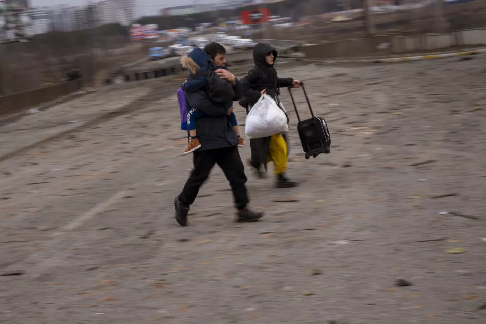 A Ukrainian family runs as artillery echoes nearby, while fleeing Irpin in the outskirts of Kyiv, 