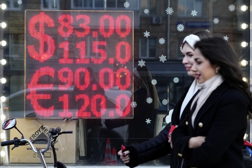 People walk past a currency exchange office screen displaying the exchange rates of US dollar and euro to Russian roubles in Moscow's downtown