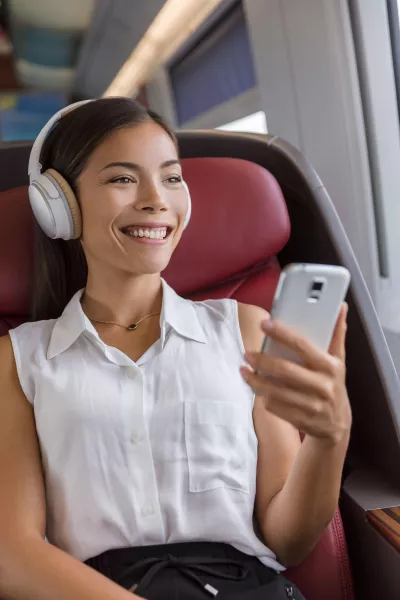 woman using phone app and wireless headphones to listen to music
