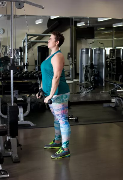 Woman using weights machine in gym