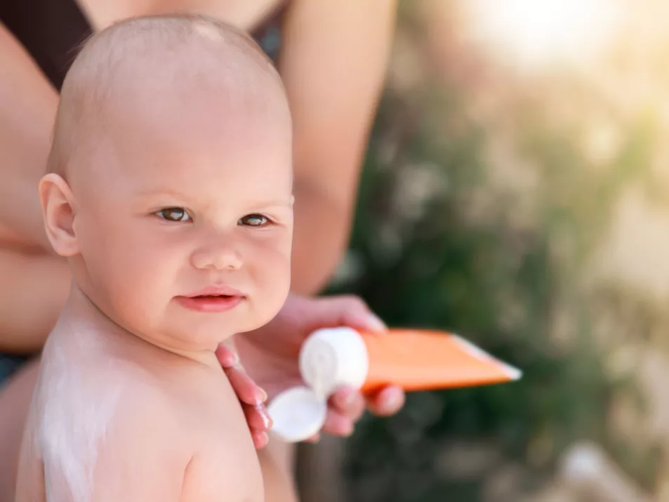 Mum putting suncream on baby