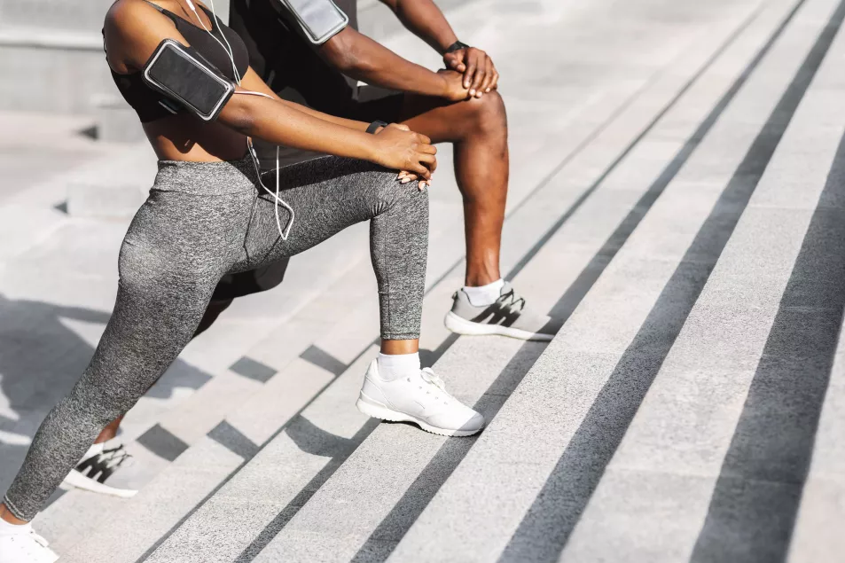 Couple in sportswear exercising together outdoors and stretching leg muscles