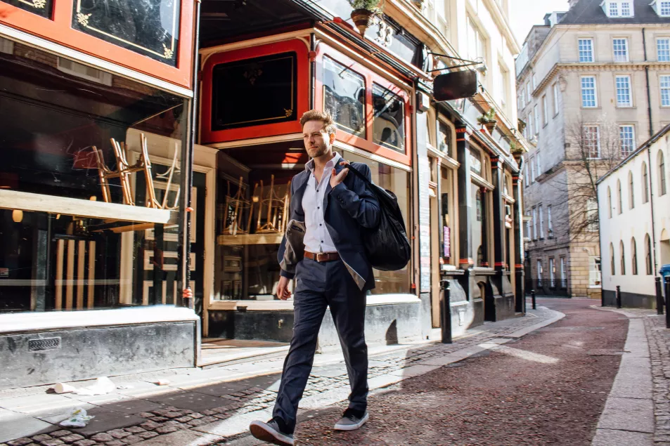 Businessman walking to work in trainers and carrying gym bag 