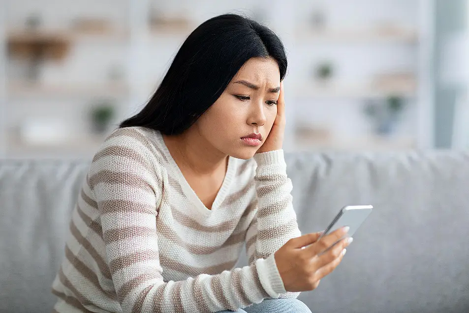 Woman holding mobile phone looking worried