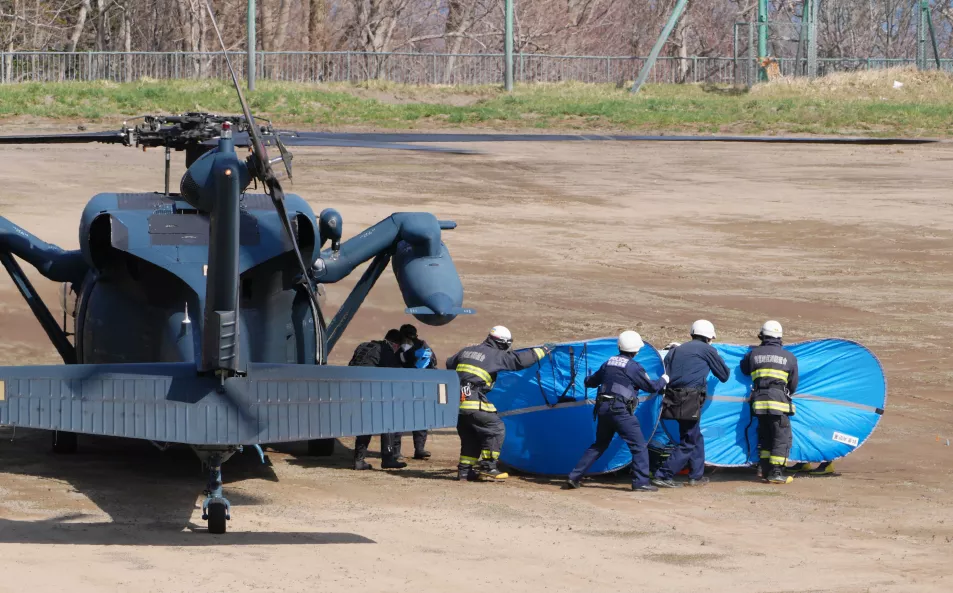 Firefighters transfer a rescued person from a helicopter in Shari, in the northern island of Hokkaido Sunday, April 24, 2022. The Japanese Coast Guard said Sunday that rescue helicopters found four of the 26 people on a tour boat missing in the frigid waters of northern Japan since the day before, but their conditions are unknown. 