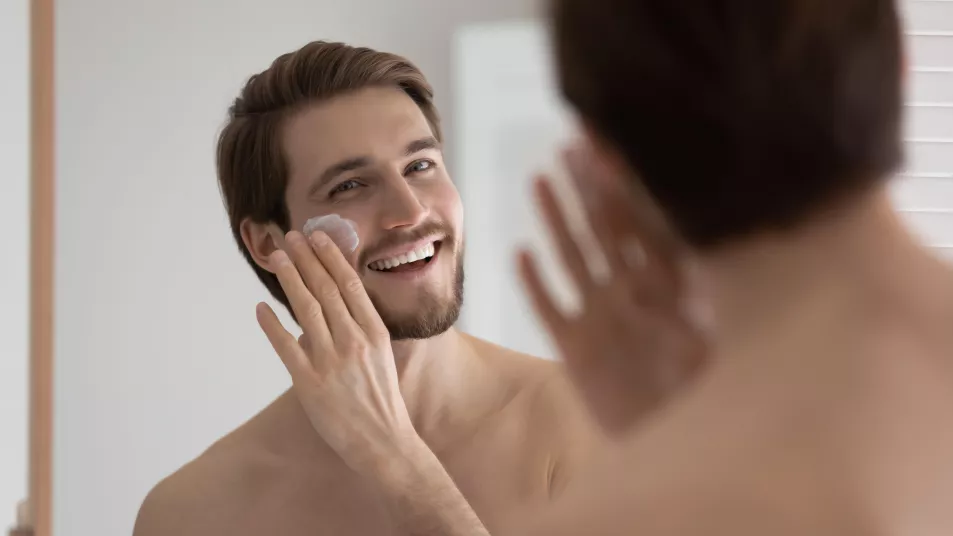 Man applying sunscreen in the mirror