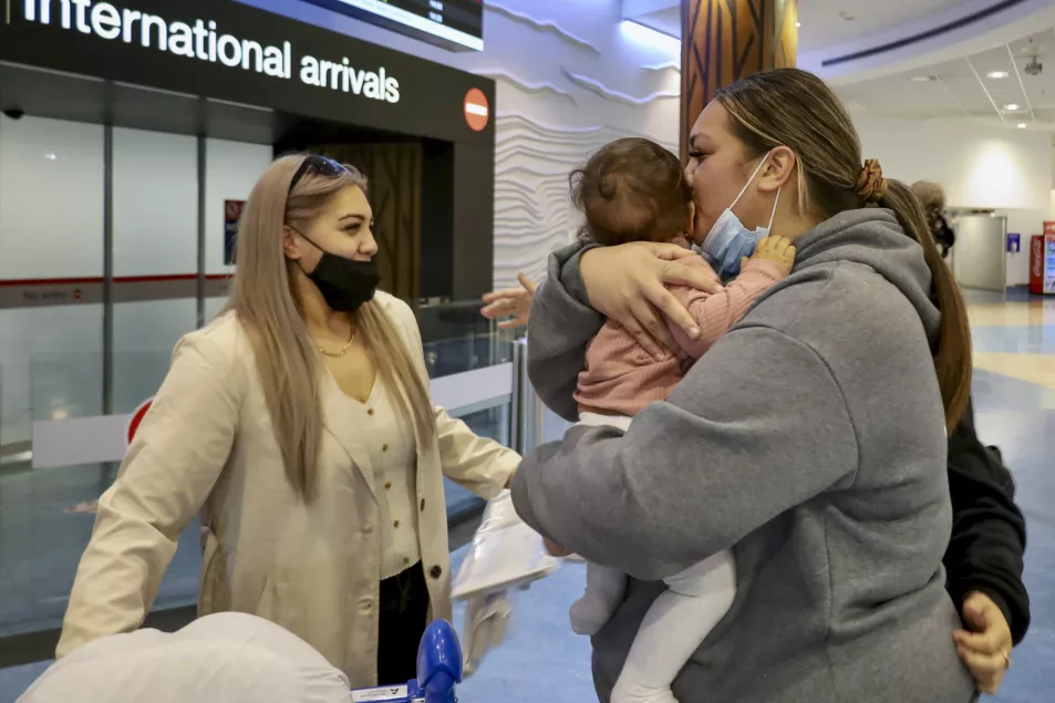 Families embrace after a flight from Los Angeles arrived at Auckland International Airport as New Zealand's border opened for visa-waiver countries on Monday