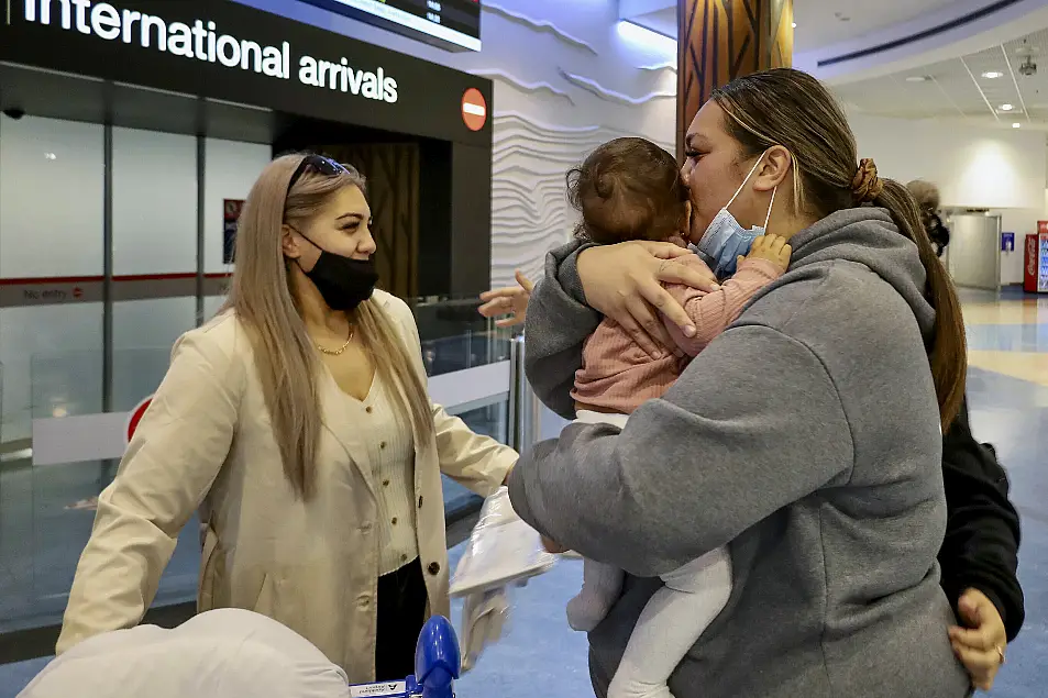 Families embrace after a flight from Los Angeles arrived at Auckland International Airport as New Zealand's border opened for visa-waiver countries on Monday