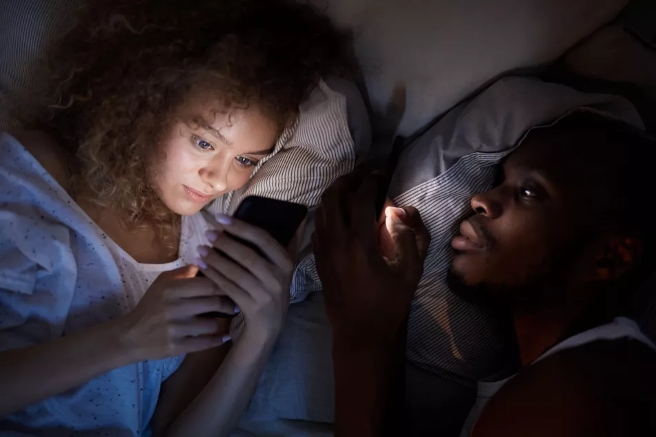 Young couple on phones in bed